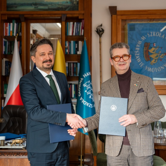 dwóch mężczyzn w gabinecie podaje sobie dłonie po podpisaniu porozumienia