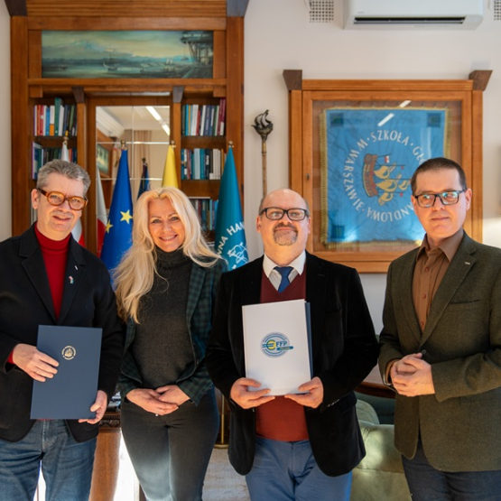 trzech mężczyzn i kobieta pozują do zdjęcia w gabinecie po podpisaniu porozumienia