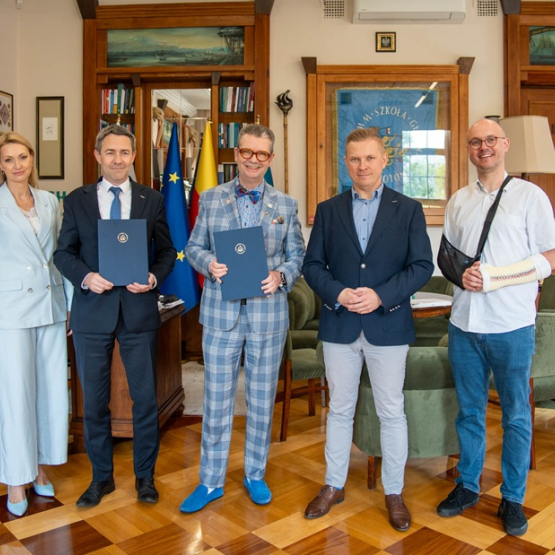 Kilka osób pozuje do zdjęcia w gabinecie po podpisaniu porozumienia