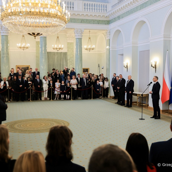 kilkadziesiąt osób na uroczystości u prezydenta; środek pomieszczenia pusty; zgromadzeni stoją przy ścianach