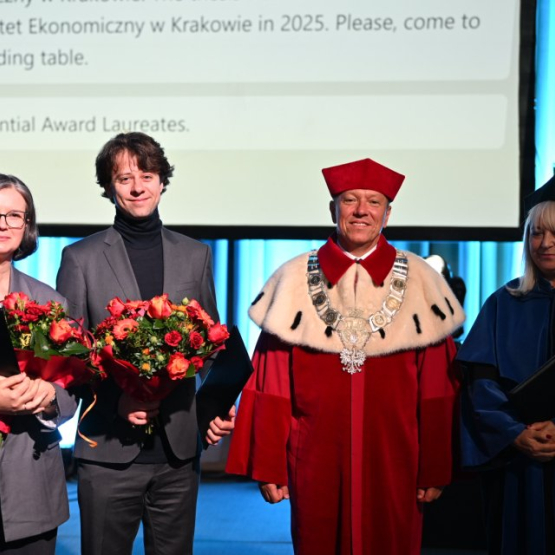 cztery osoby na zdjęciu, w tym laureat nagrody z bukietem kwiatów oraz rektor i prorektor uczelni
