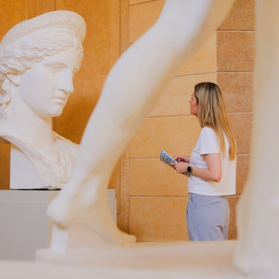 kobieta patrzy na antyczną rzeźbę w muzeum