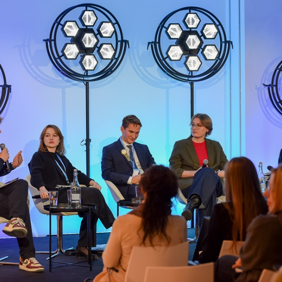 czworo młodych studentów rozmawia na panelu; z tyłu światła