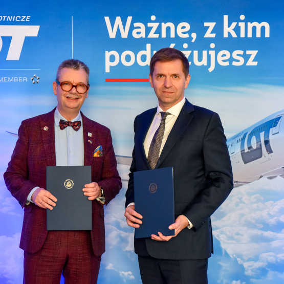 dwóch mężczyzn na tle ścianki z samolotem
