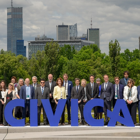 grupa osób na tle panoramy Warszawy, z przodu niebieski napis CIVICA