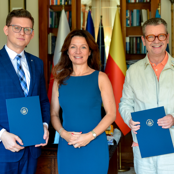 dwóch mężczyzn i kobieta po podpisaniu porozumienia pozują do zdjęcia w gabinecie