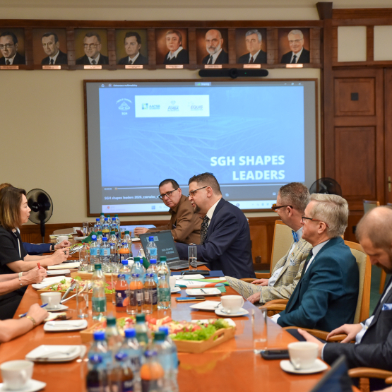 kilkanaście osób rozmawia przy stole konferencyjnym, w tle wyświetlana prezentacja