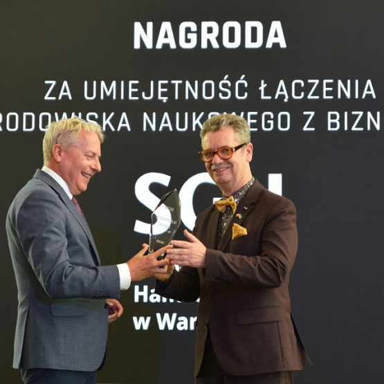 jeden mężczyzna przekazuje drugiemu statuetkę na gali