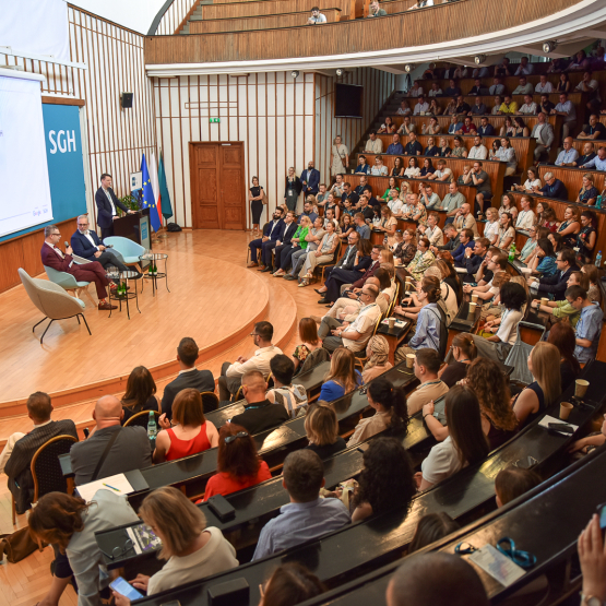aula uczelniana wypełniona tłumem gości, na scenie rozmawia dwóch mężczyzn