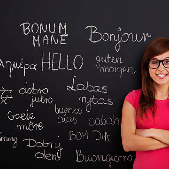 lektorka języków obcych stoi przed tablicą, na której widnieją wypisane kredą słowa w różnych językach