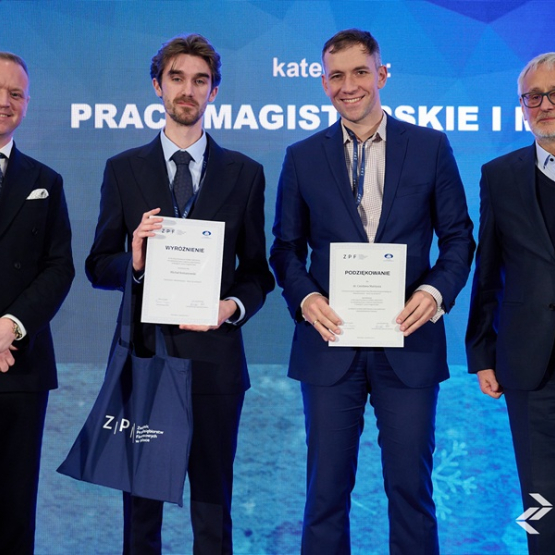 czterech mężczyzn na scenie; dwóch trzyma w rękach dyplomy z podziękowaniami