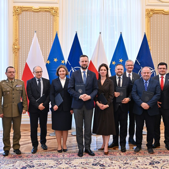 grono oficjeli pozuje do zdjęcia; w tle flagi Polski, UE, NATO