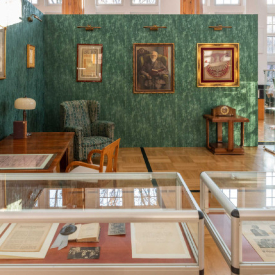 zdjęcie wystawy; z przodu przezroczyste gabloty, w tle rekonstrukcja gabinetu z lat 20.30. XX w.