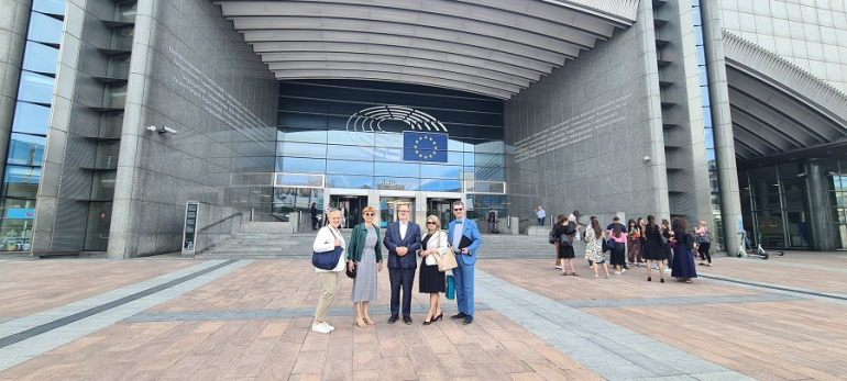 grupka osób stoi przed budynkiem Parlamentu Europejskiego