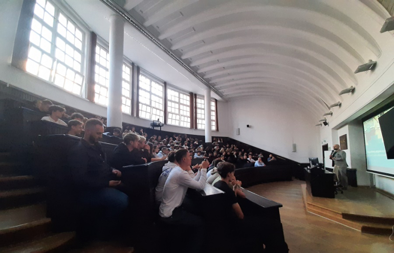 aula na uczelni wypełniona uczniami szkół srednich, na katedrze wykładowca