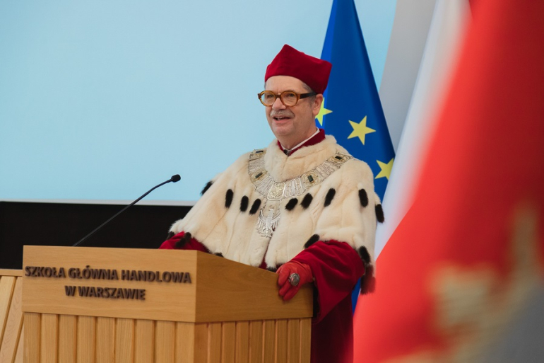 mężczyzna w todze rektorskiej za mównicą