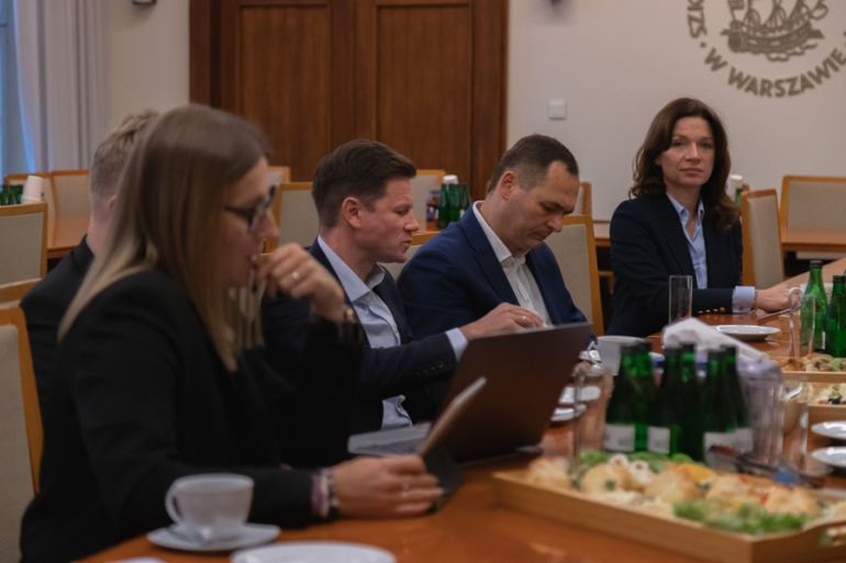 kilka osób dyskutuje przy zastawionym stole