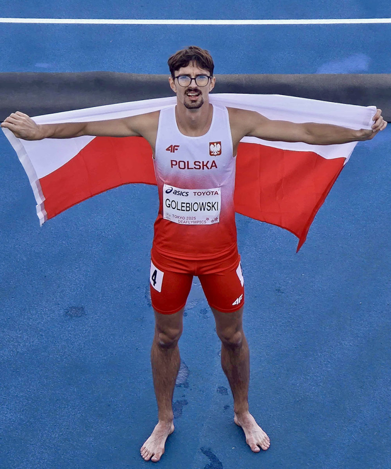 mężczyzna na bieżni z rozpostartą flagą Polski na plecach