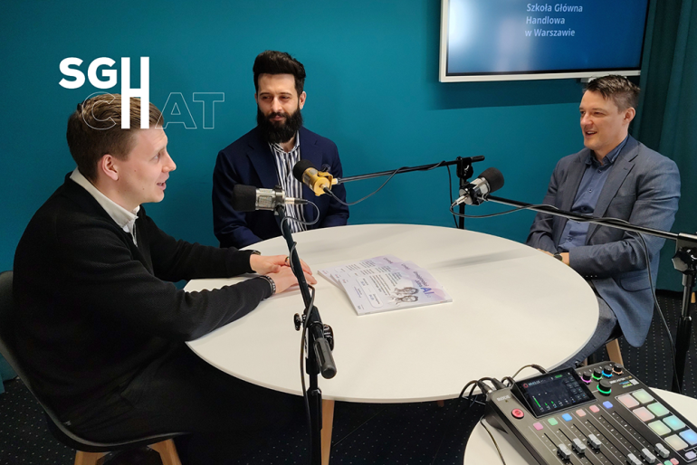 trzech panów siedzących przy stole z mikrofonami