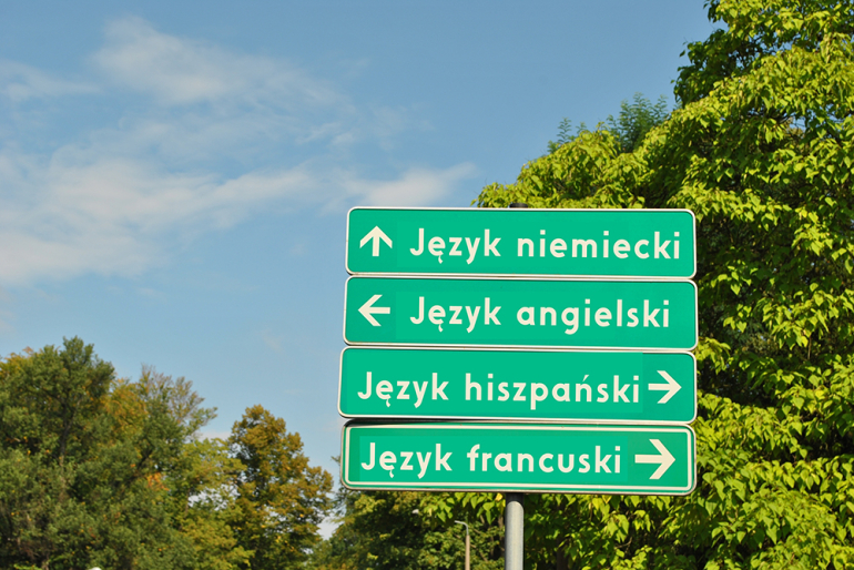 na zdjęciu drogowskazy drogowe z napisami języków obcych