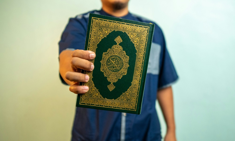 mężczyzna trzymający w ręku Koran