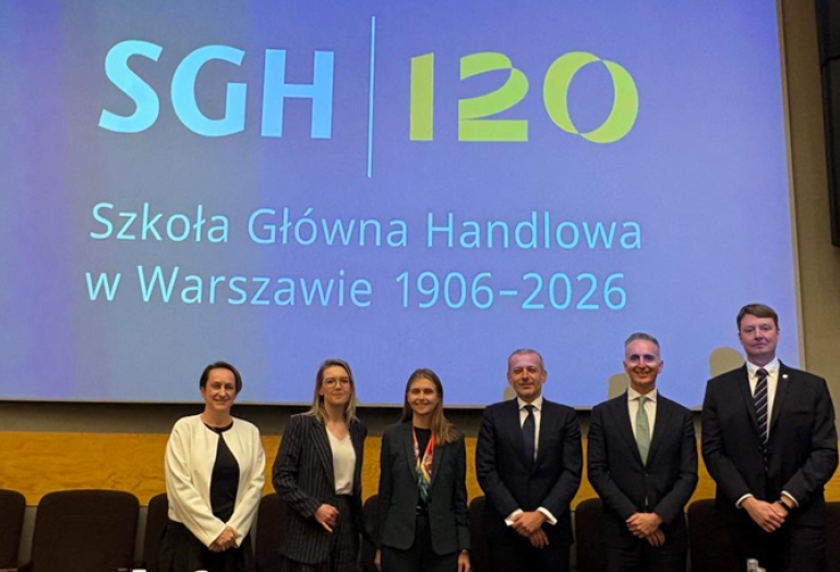 kilka osób podczas konferencji stoi za katedrą i pozuje doz zdjęcia