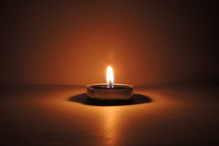 płonąca świeczka w ciemnym pomieszczeniu