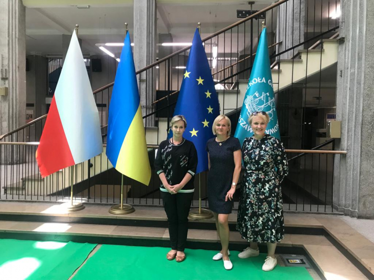 trzy kobiety na tle flag Polski, Ukrainy, UE i SGH