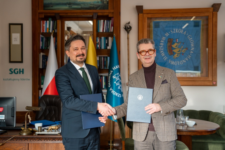 dwóch mężczyzn w gabinecie podaje sobie dłonie po podpisaniu porozumienia