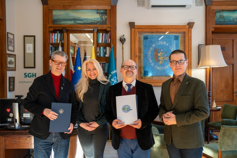 trzech mężczyzn i kobieta pozują do zdjęcia w gabinecie po podpisaniu porozumienia