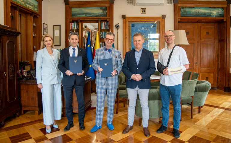 Kilka osób pozuje do zdjęcia w gabinecie po podpisaniu porozumienia