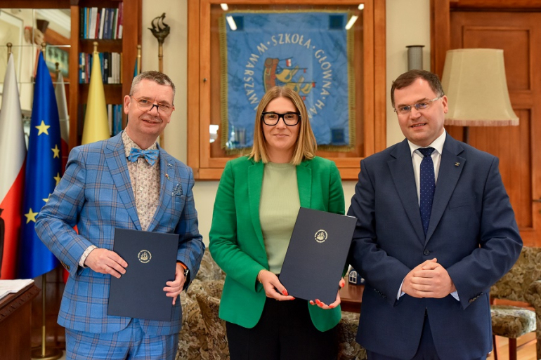 dwóch mężczyzn i kobieta pozują do zdjęcia w gabinecie po podpisaniu porozumienia; mężczyzna i kobieta trzymają w rękach teczki z dokumentem