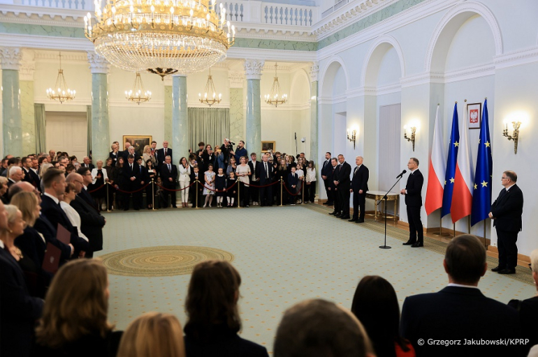 kilkadziesiąt osób na uroczystości u prezydenta; środek pomieszczenia pusty; zgromadzeni stoją przy ścianach