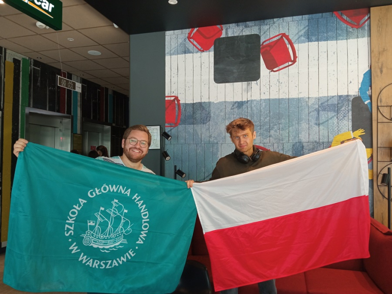 dwóch mężczyzn trzyma flagi Polski i SGH