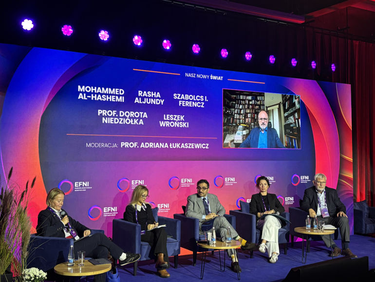 kilka osób siedzi na scenie podczas panelu