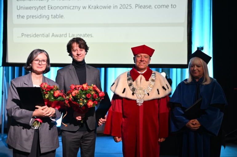 cztery osoby na zdjęciu, w tym laureat nagrody z bukietem kwiatów oraz rektor i prorektor uczelni