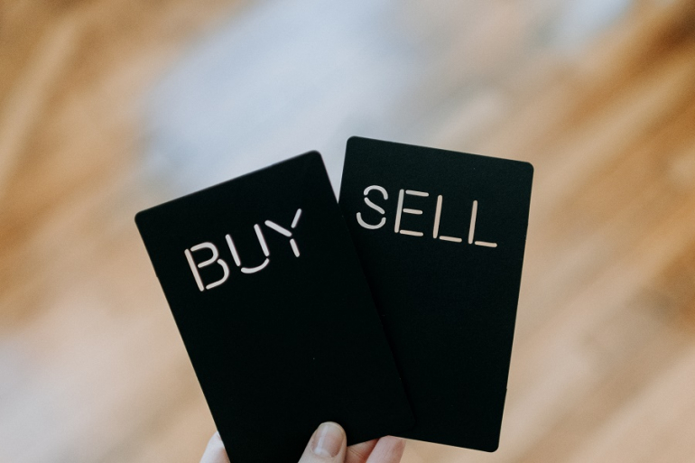 dwie czarne karty z wyciętym napisem "sell" i "buy"