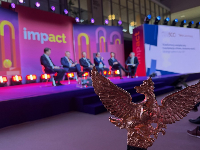 na pierwszym planie rzeźba godła dziennika "Rzeczpospolita" w tle paneliści rozmawiają na kongresie