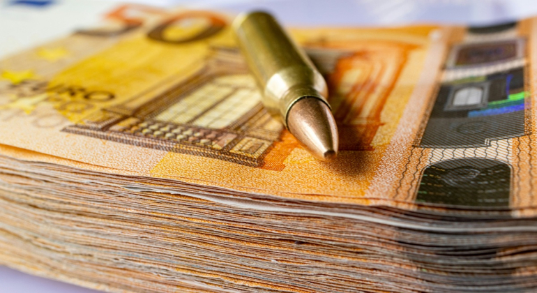 zdjęcie naboju/ łuski po naboju na stosie banknotów