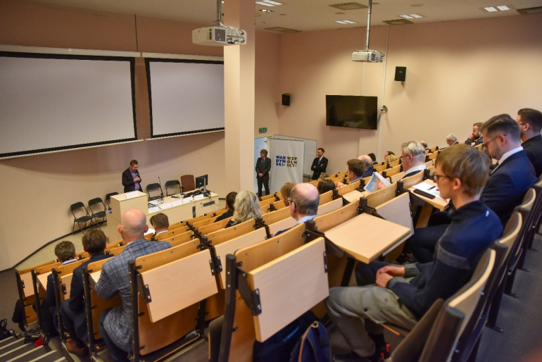 licznie zgromadzeni uczestnicy konferencji siedzą w uczelnianej auli