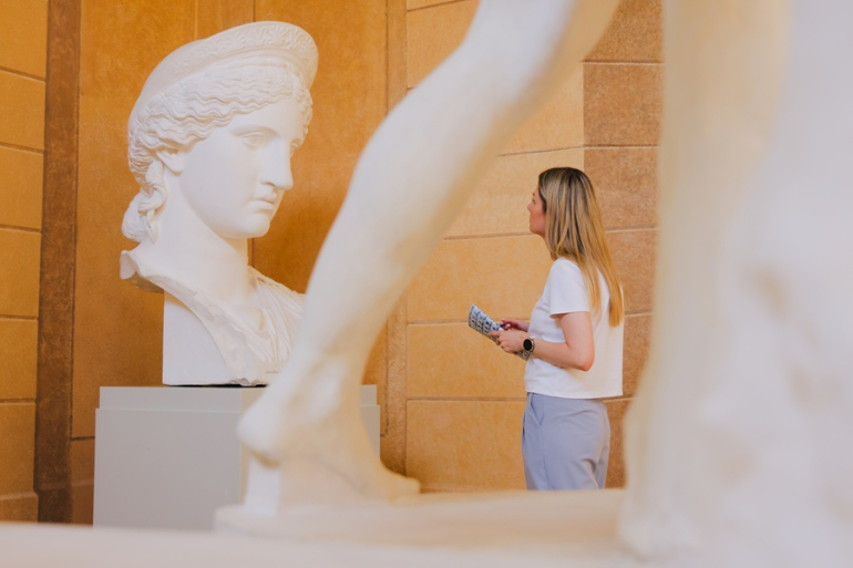kobieta patrzy na antyczną rzeźbę w muzeum