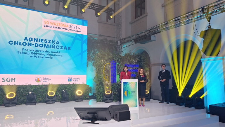 trzy osoby stoją na scenie, kobieta przemawia