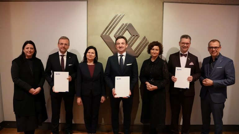 kilka osób pozuje do zdjęcia; trzy z nich trzymają podpisane dokumenty