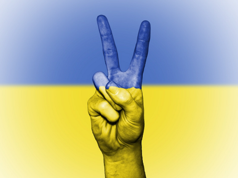 znak wiktorii wykonywany dłonią wpisany we flagę Ukrainy