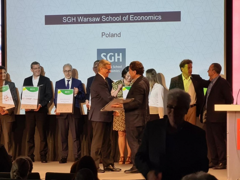 man receives certificate at ceremony; around a dozen people gathered on stage