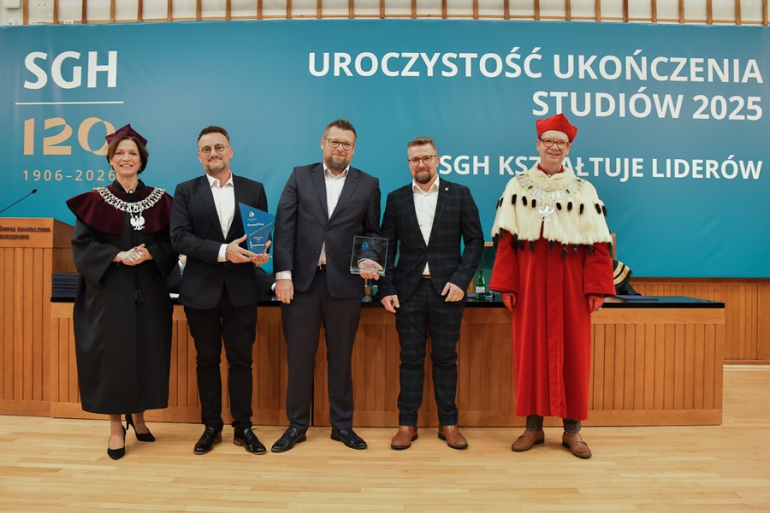 trzech mężczyzn w garniturach oraz kobieta i mężczyzna w togach rektorskich stoją na scenie