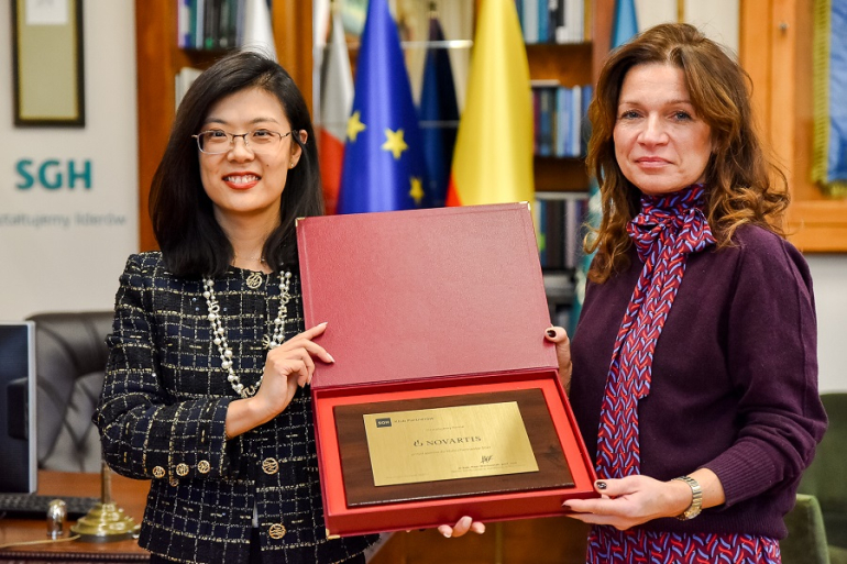 diw kobiety stoją w gabinecie i trzymają w rękach mosiężną tablicę