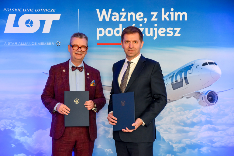 dwóch mężczyzn na tle ścianki z samolotem