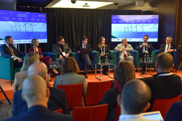 kilka osób rozmawia na panelu; ludzie siedzą na widowni