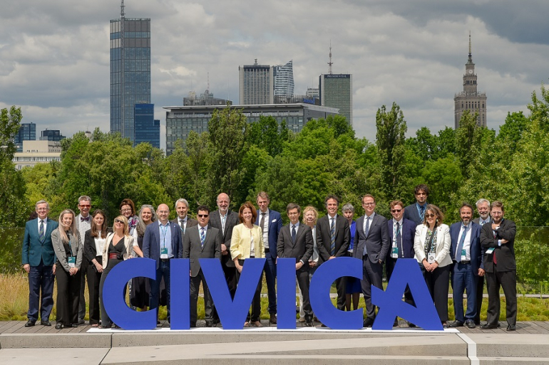 grupa osób na tle panoramy Warszawy, z przodu niebieski napis CIVICA